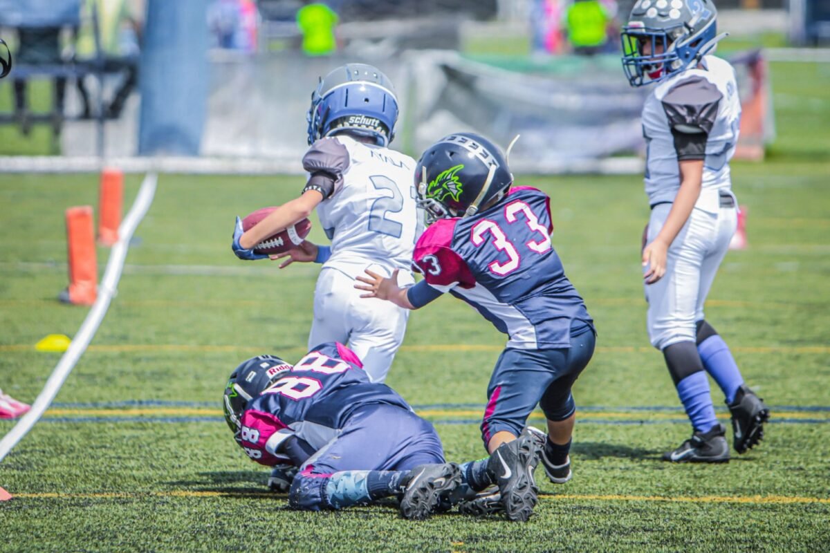 Coach measuring a youth football player's chest over shoulder pads for custom uniform sizing